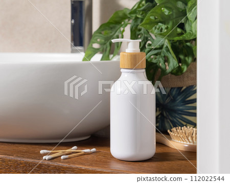 White one pump bottle near basin and green monstera on wooden countertop in bath, mockup White one pump bottle near basin and green monstera on wooden countertop in bath, mockup 112022544