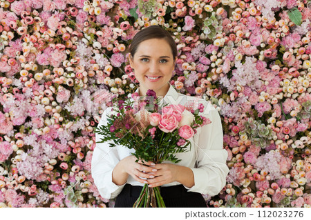 Attractive lady with flowers. Happy brunette woman indoor portrait 112023276