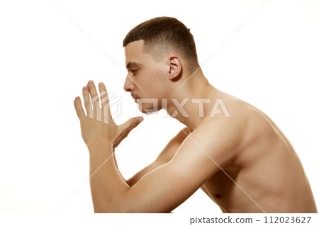 Side view of thoughtful shirtless man with serious and focused expression folded his hands together against white studio background. Side view of thoughtful shirtless man with serious and focused expression folded his hands together against white studio background. 112023627