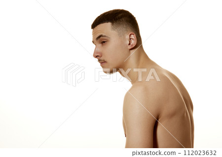 Side view photo of young man slouches against white studio background. Incorrect posture, beauty and confidence. 112023632