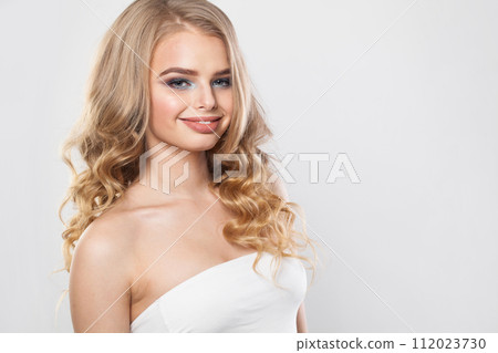 Smiling blonde model woman with perfect hairstyle, fresh clear skin and makeup on white background.  112023730