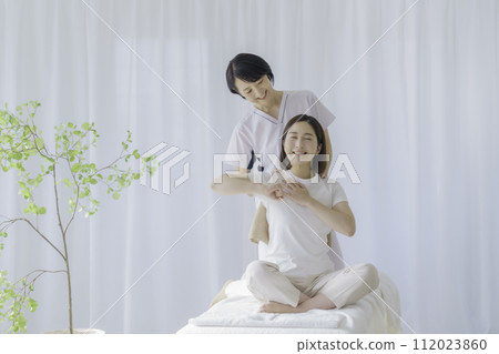 A middle-aged female chiropractor who performs treatment on young women A middle-aged female chiropractor who performs treatment on young women 112023860