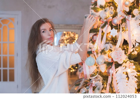 Cute woman decorating the Christmas tree at home Cute woman decorating the Christmas tree at home 112024053