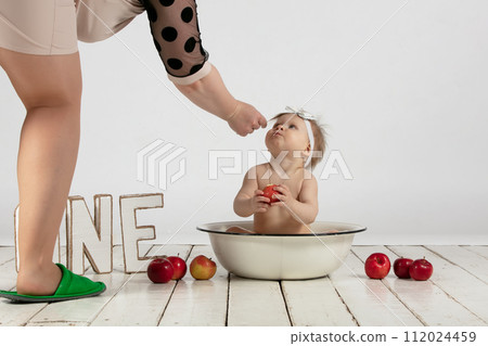 Mom and a one-year-old baby. A beautiful little girl is being prepared for a photo shoot. Mom's hands and little daughter. 112024459