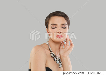 Elegant jewelry model woman with dark brown hair and shiny fresh skin wearing diamond earring 112024643