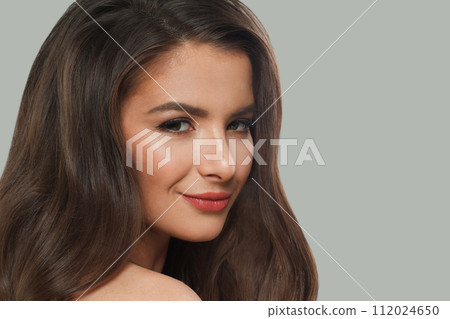 Cheerful woman brunette with long dark healthy wavy hair and makeup  on gray background.  112024650