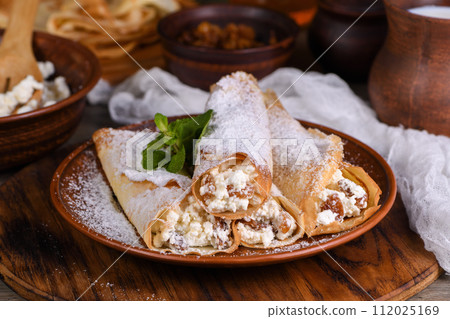 Thin pancakes stuffed with cottage cheese, honey and raisins Thin pancakes stuffed with cottage cheese, honey and raisins 112025169