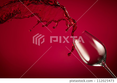 Glass and red wine splash on a red background. 112025473