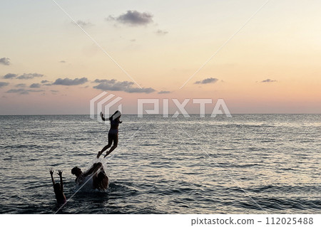 Family having fun on sea beach. Kid jumping in the sea. Summer vacation, travel and holiday concept. 112025488