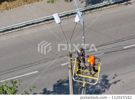 Workers installing a new street lamp. Workers installing a new street lamp. 112025582