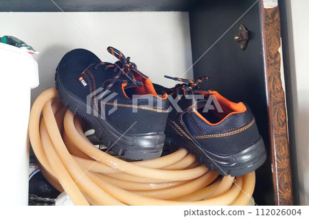 Boots Resting on Coiled Orange Hose Inside a Cabinet Boots Resting on Coiled Orange Hose Inside a Cabinet 112026004