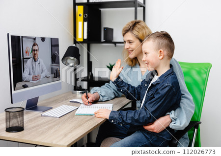 Young mother and child enjoying digital era, having online telemedicine consultation with remote doctor by professional paediatrician about cold and flu virus treatment 112026773