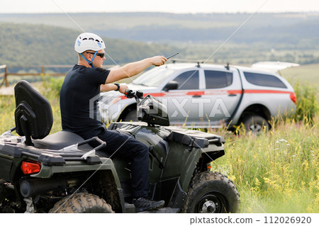 The rescuer, a beautiful athletic physique, rides an ATV in the middle of the field 112026920