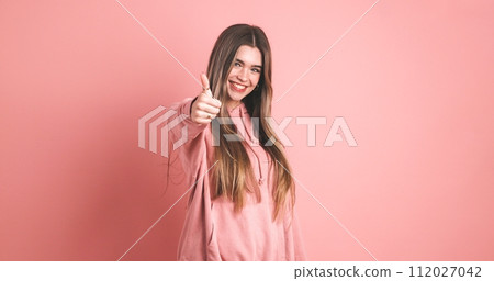 Happy young woman showing thumb up gesture 112027042