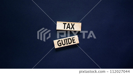 Tax guide symbol. Concept words Tax guide on beautiful wooden block. Beautiful black table black background. Business and Tax guide concept. Copy space. Tax guide symbol. Concept words Tax guide on beautiful wooden block. Beautiful black table black background. Business and Tax guide concept. Copy space. 112027044