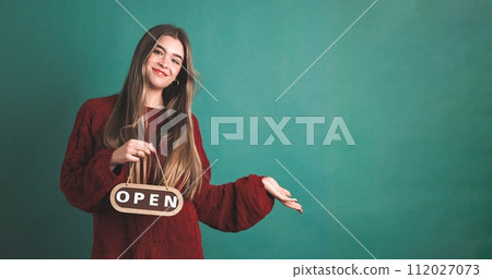 Happy woman with open inscription standing in studio 112027073