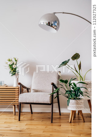 Stylish modern Scandinavian interior of living room with candles and fresh flowers on wooden console, retro style armchair, floor lamp and potted green home plants. Cozy home interior design. Vertical Stylish modern Scandinavian interior of living room with candles and fresh flowers on wooden console, retro style armchair, floor lamp and potted green home plants. Cozy home interior design. Vertical 112027325