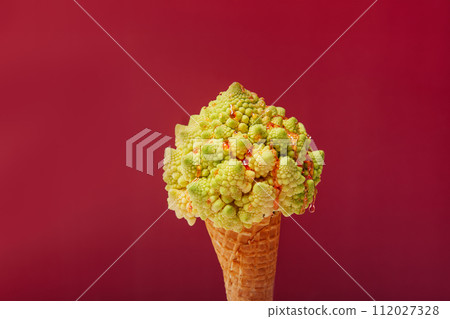 Plant based Ice cream concept. Waffle cone with Romanesco cabbage with dripping fruit sauce as vegetarian dessert on pastel green background. Creative healthy vegetarian and vegan food concept Plant based Ice cream concept. Waffle cone with Romanesco cabbage with dripping fruit sauce as vegetarian dessert on pastel green background. Creative healthy vegetarian and vegan food concept 112027328