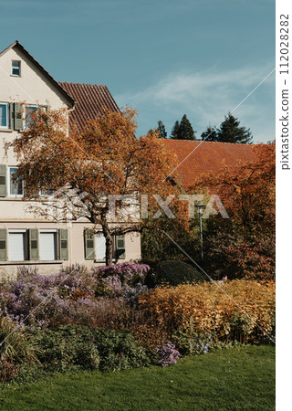 House with nice garden in fall. Flowers in the City Park of Bietigheim-Bissingen, Baden-Wuerttemberg, Germany, Europe. Autumn Park and house, nobody, bush and grenery House with nice garden in fall. Flowers in the City Park of Bietigheim-Bissingen, Baden-Wuerttemberg, Germany, Europe. Autumn Park and house, nobody, bush and grenery 112028282