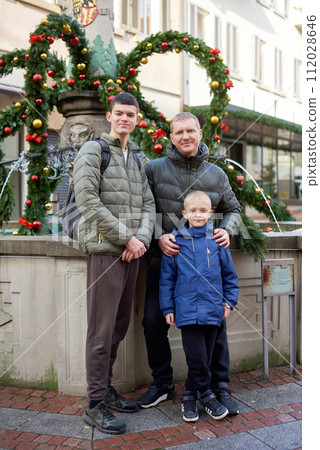 Joyful Family Portrait: Father and Two Sons by Festive Vintage Fountain. 112028646