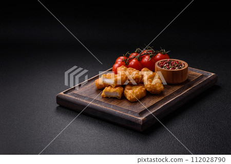 Delicious fresh crispy chicken nuggets on a dark concrete background 112028790