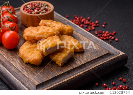 Delicious fresh crispy chicken nuggets on a dark concrete background 112028794