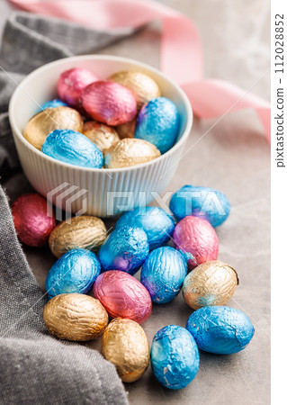 Easter chocolate eggs wrapped in aluminium foil on kitchen table. 112028852