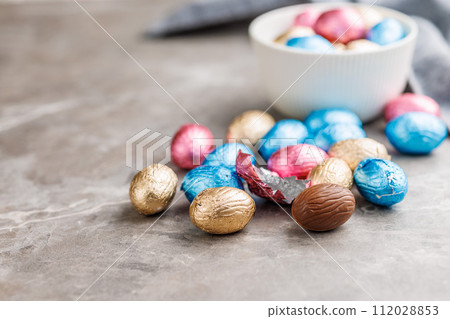Easter chocolate eggs wrapped in aluminium foil on kitchen table. 112028853