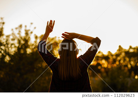 Woman with Headphones Enjoying Sunset Silhouette 112029623