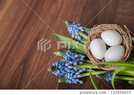 Happy Easter greeting card. Eggs in a nest and Muscari flowers.. 112030037