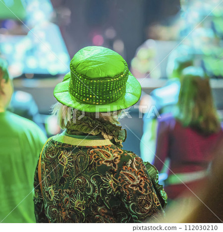 Back view of woman in green hat celebrating with people St. Patrick's Day 112030210