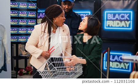 Crazy people fighting in retail store to catch black friday seasonal sales, aggressive women pushing each other at shop entrance. Promotional event with anxious customers at shopping mall. 112031108