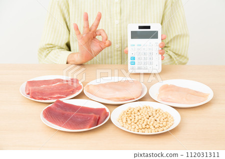 一名中年婦女拿著富含蛋白質的食物和計算器，並做一個圓圈標誌 112031311