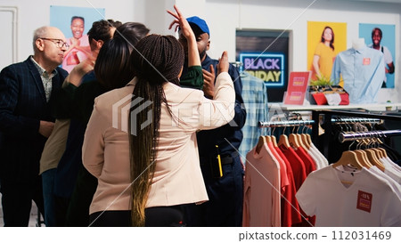Diverse customers waiting in line for promotions and special offers, standing behind red tape at clothing store entrance. Shoppers pushing retail store employee, obsessed crowd. Diverse customers waiting in line for promotions and special offers, standing behind red tape at clothing store entrance. Shoppers pushing retail store employee, obsessed crowd. 112031469