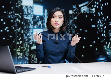 Broadcaster providing latest news and exclusive details, reading headlines on international tv channel. Asian journalist working on media segment during late night show, news studio reportage. 112031490