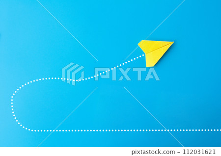 Top view of yellow paper airplane making a U turn on blue background. Top view of yellow paper airplane making a U turn on blue background. 112031621