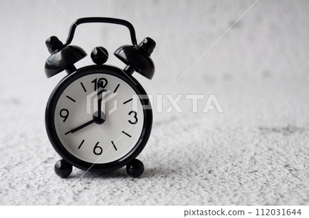 Black alarm clock pointing at 8am with customizable space for text. Copy space. 112031644