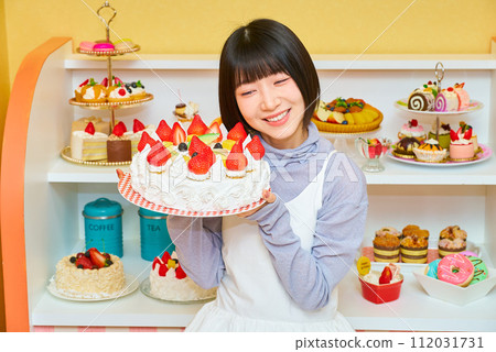 A young woman holding a whole cake A young woman holding a whole cake 112031731
