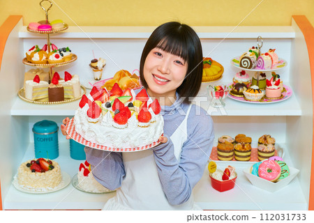 A young woman holding a whole cake A young woman holding a whole cake 112031733