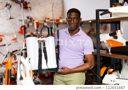Man deciding on best garden sprayer in garden equipment shop 112031887