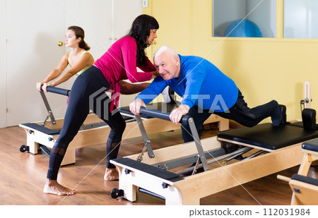 Female trainer working with senior man at rehab. Female trainer helping senior man at sport gym 112031984