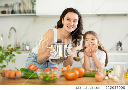 Mom and little daughter are standing at kitchen table with dishes in their hands. Mom and little daughter are standing at kitchen table with dishes in their hands. 112032008