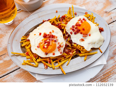 Fried eggs with french fries sprinkled with cured ham 112032139