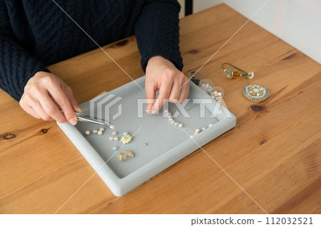 Woman's hands making beaded accessories 112032521