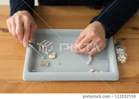 Woman's hands making beaded accessories 112032539