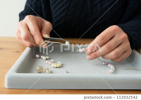 Woman's hands making beaded accessories 112032542