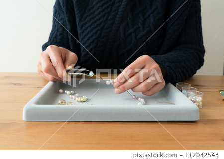 Woman's hands making beaded accessories 112032543