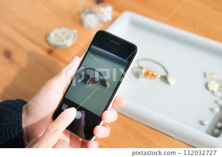 A woman taking pictures of accessories with a smartphone 112032727