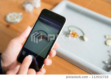 A woman taking pictures of accessories with a smartphone 112032728