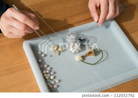 Woman's hands making beaded accessories 112032792